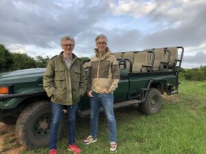 Click to enlarge Arne and Carlos beside a safari jeep in South Africa in 2020, their bright shoes standing out against the muted safari colours.
